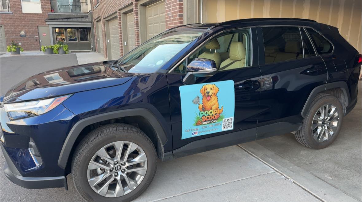 Black SUV with Poop Scoop Solutions dog logo parked on urban street